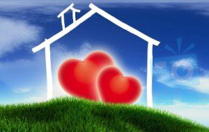Two hearts in front of a house on top of grass.